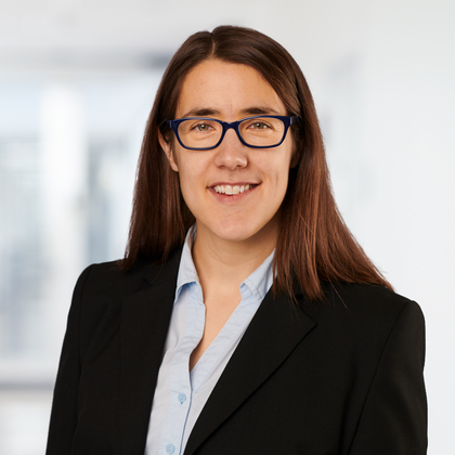A photo of a white woman with brown hair and glasses in formal clothing